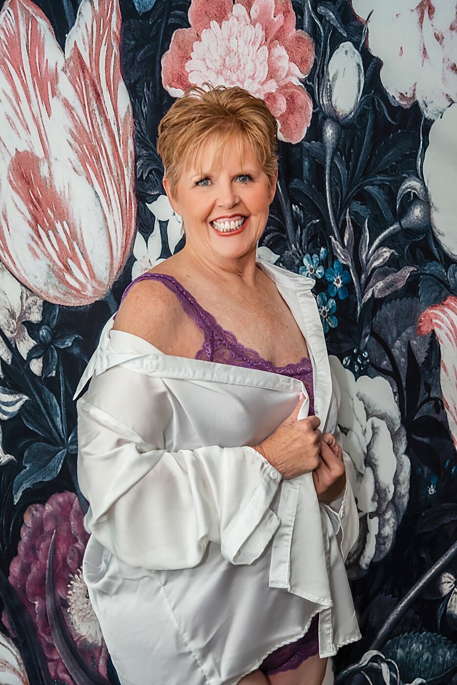 A older woman in purple lingerie poses during her boudoir session.