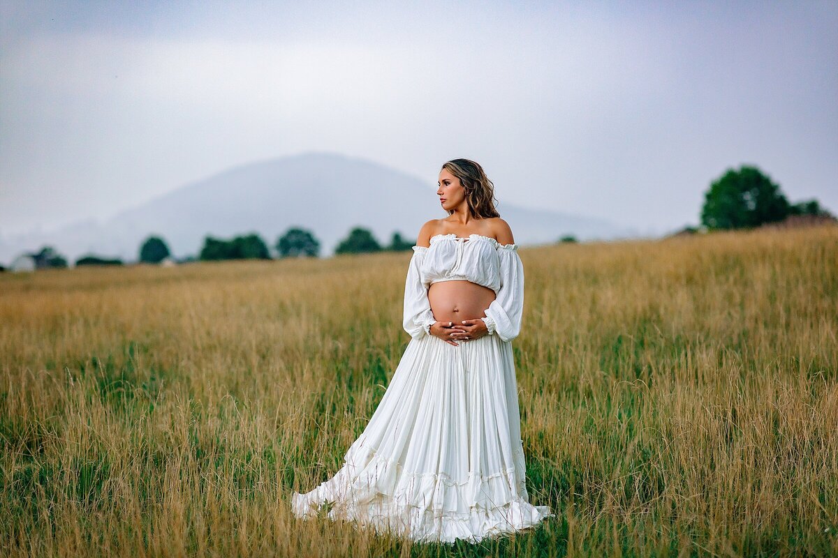 Pregnant woman in a field in a white dress