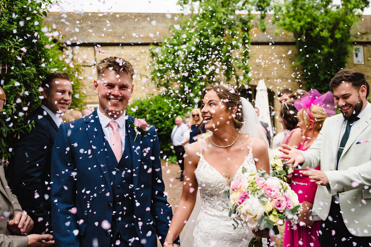 Couple wlaking through confetti in grounds of the barnsdale in rutland