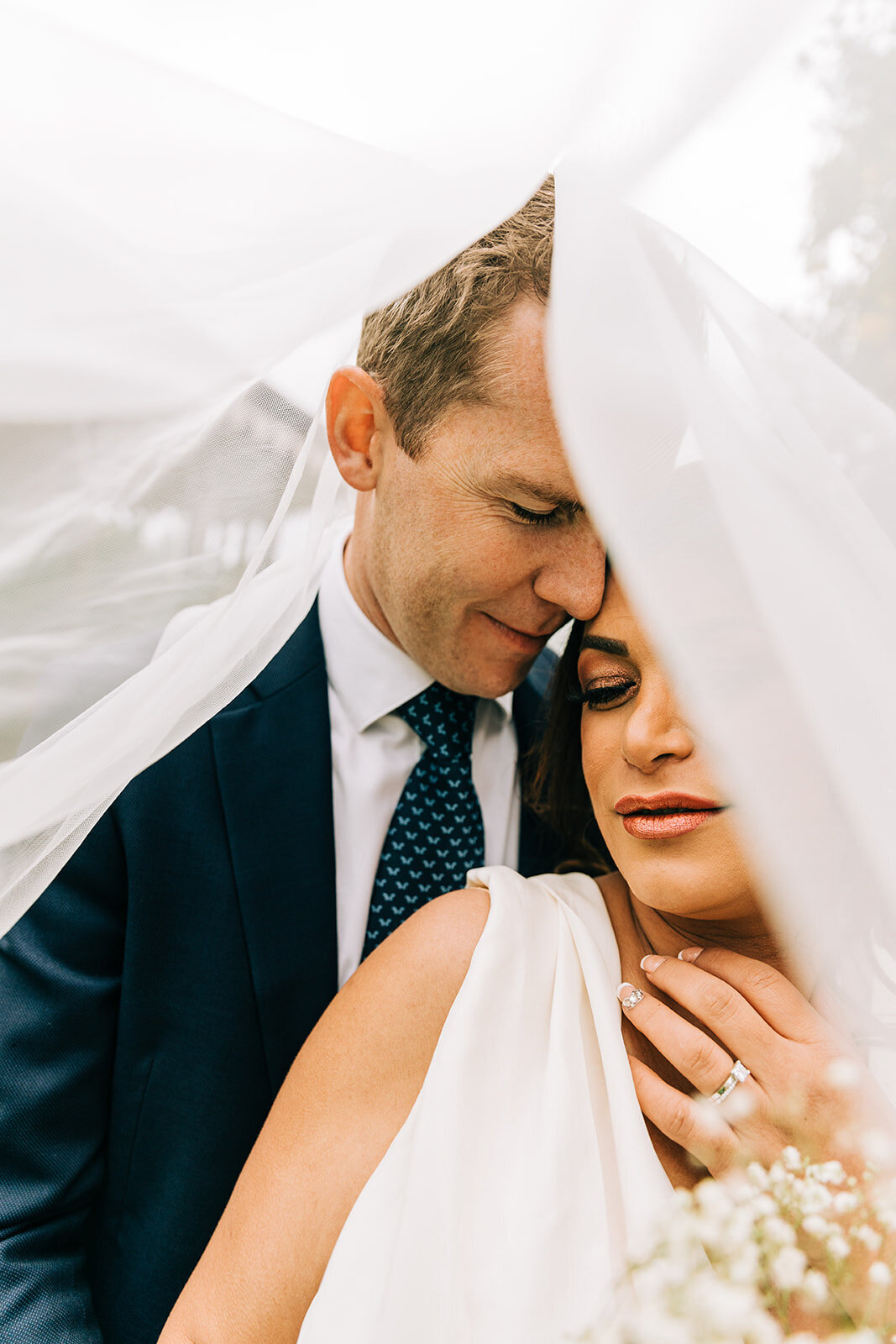 A bride and groom embracing each other under a veil