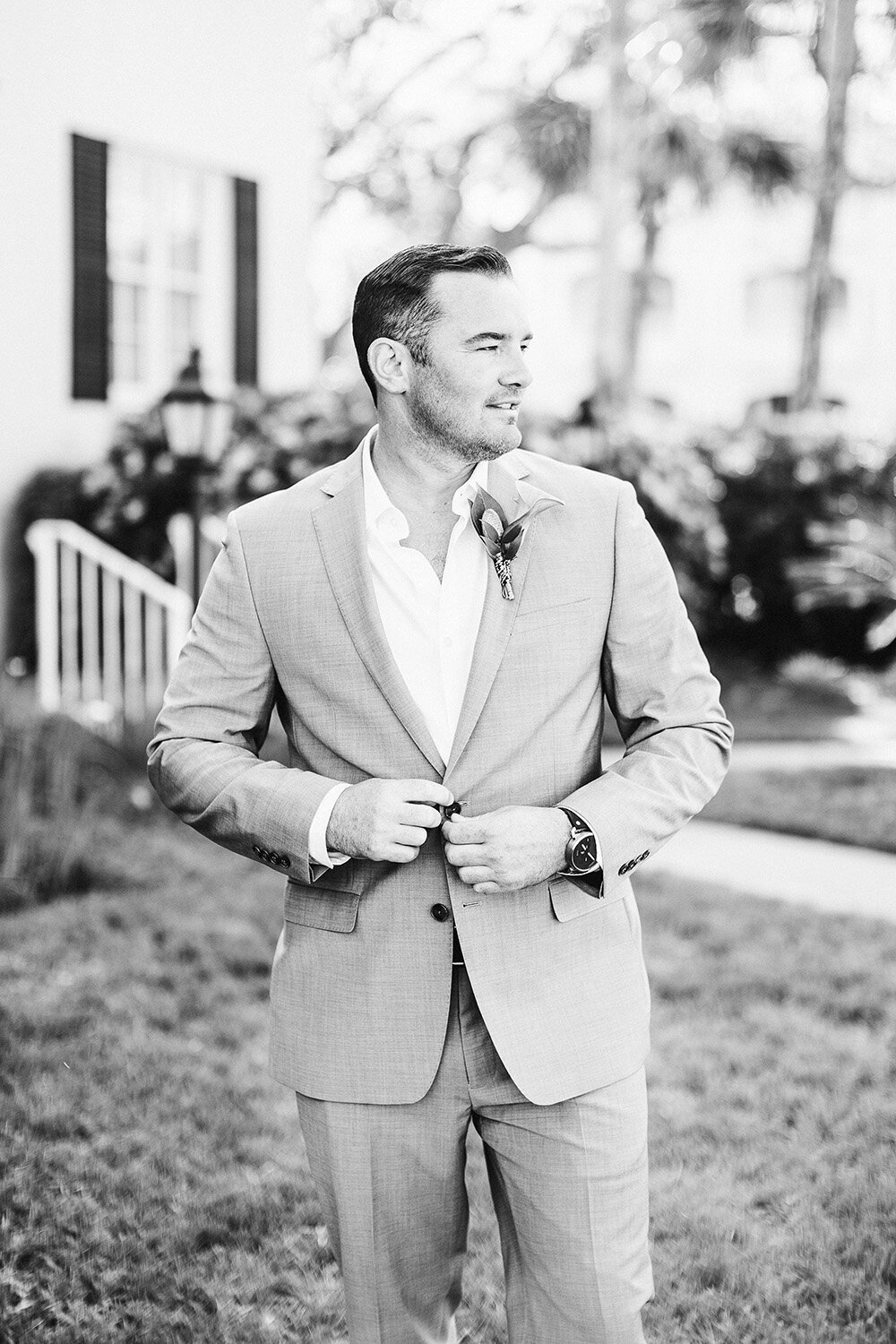Groom buttoning jacket looking right.