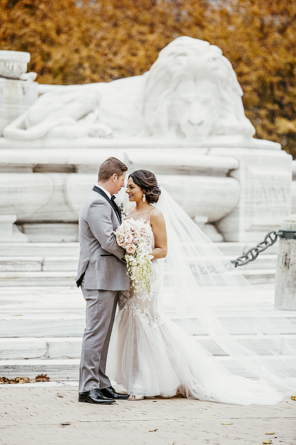 Autumn wedding with bride and groom embracing in front of monument in Buffalo, New York