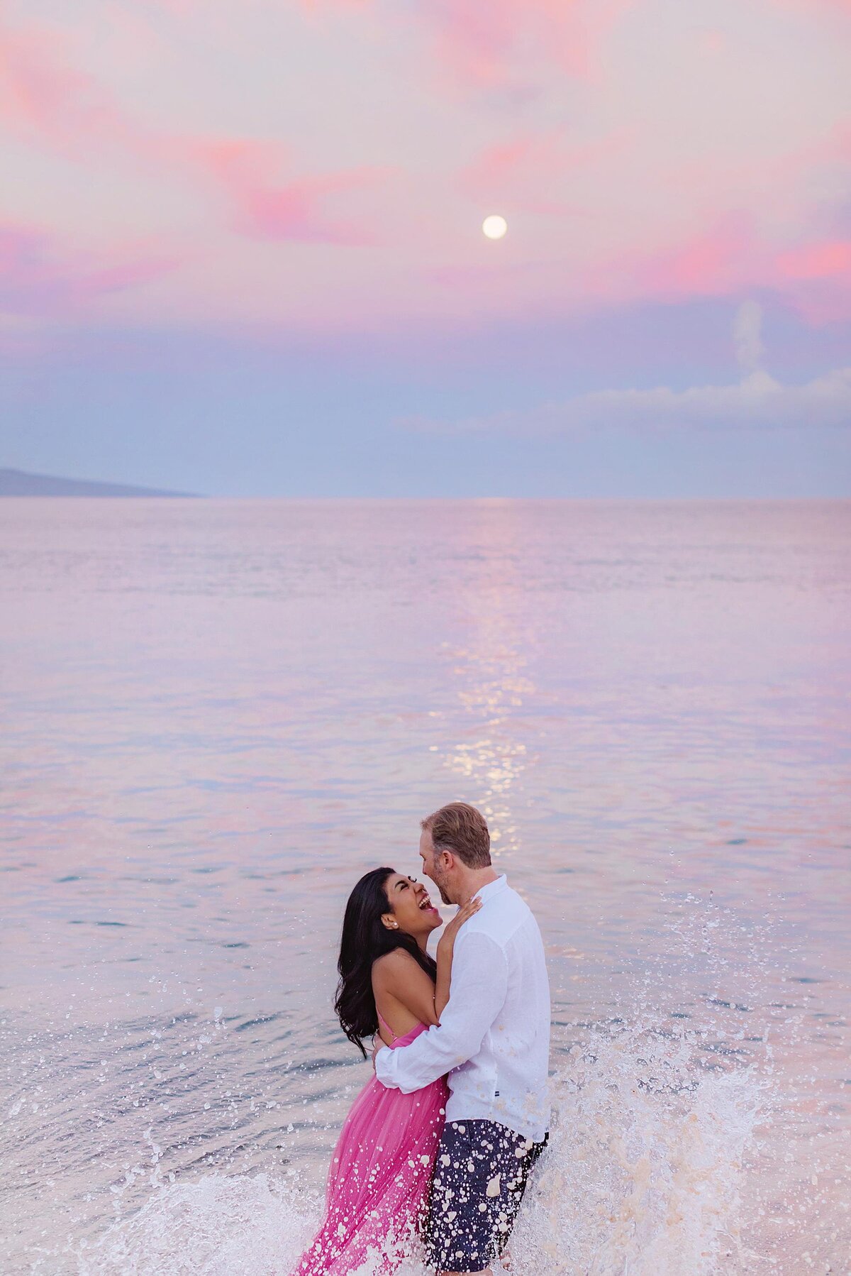 Full moon portraits on Maui with a couple laughing in the ocean during their couples photography session