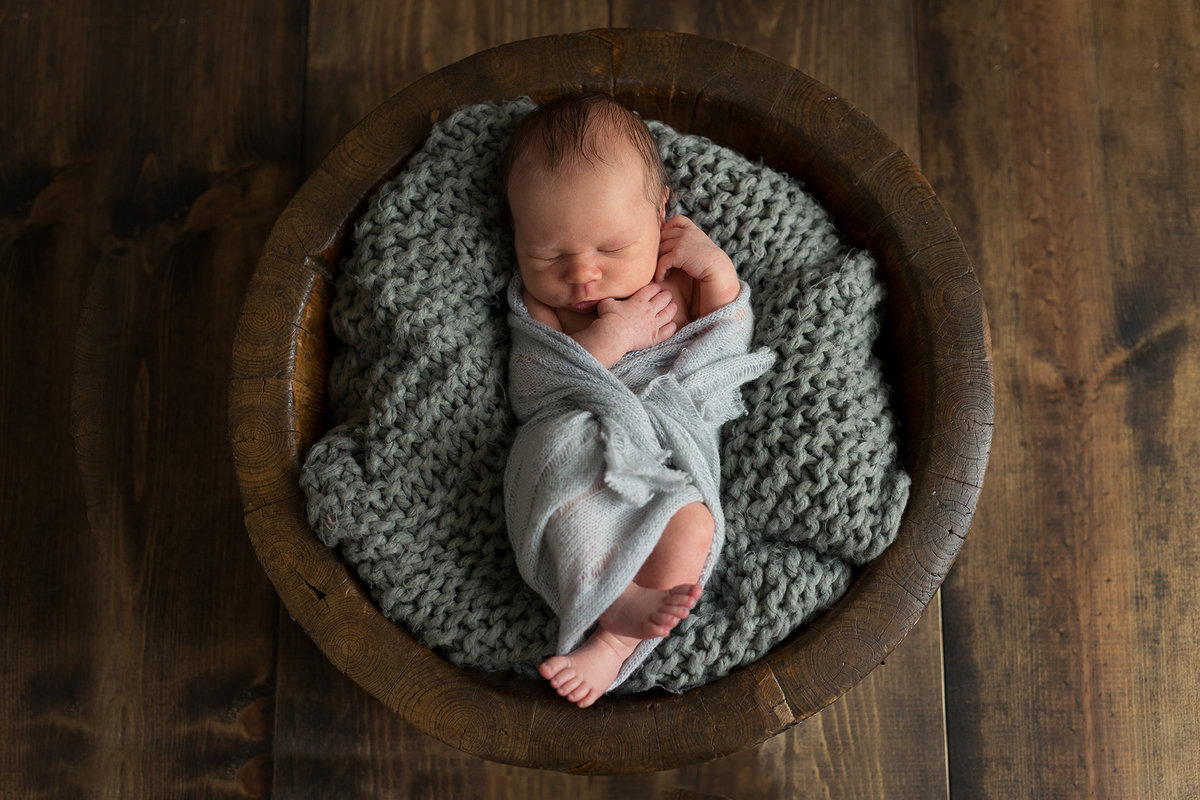 a baby boy in a gray cozy blanket