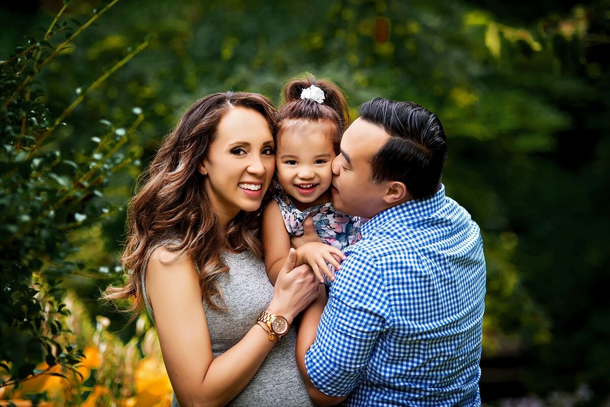 Mother, father and preschool daughter laughing at family photo session in New Westminster