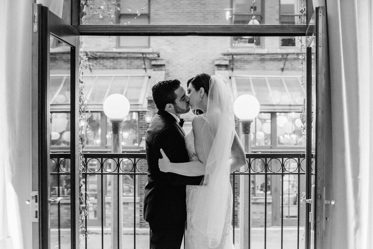 Newlyweds pose on the Juliet Balcony at the Ivy Room in Chicago to share a kiss