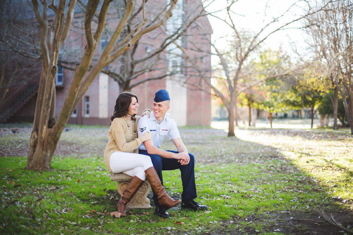 Engaged Airman and his fiancé sitting on a bench looking into each others eyes at their engagement photography session.