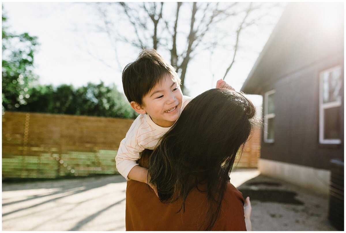 Mother carrying child outside in backyard for  garden family session in Austin by Amber Vickery Photography