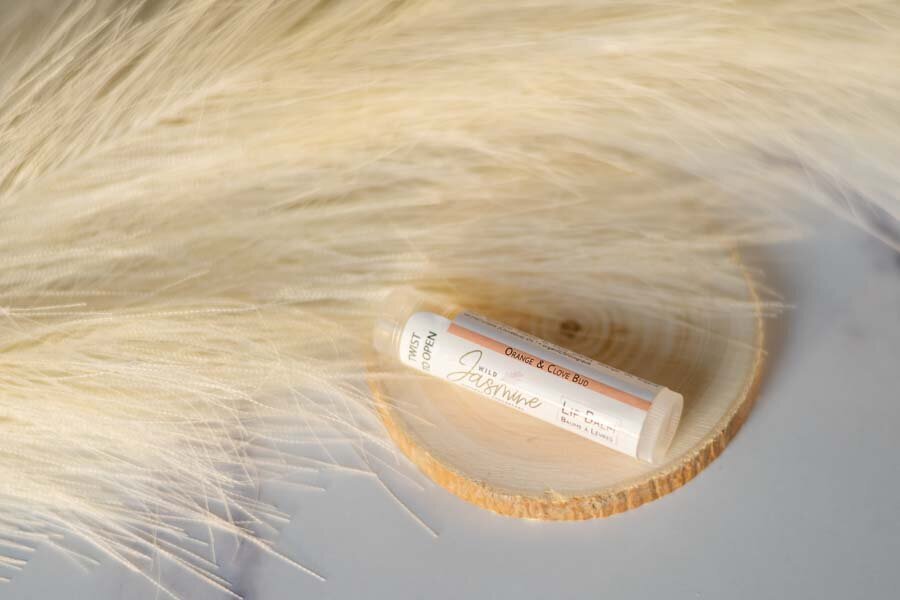 A tube of carmex lip balm on a wooden surface partially covered by soft, white fur.