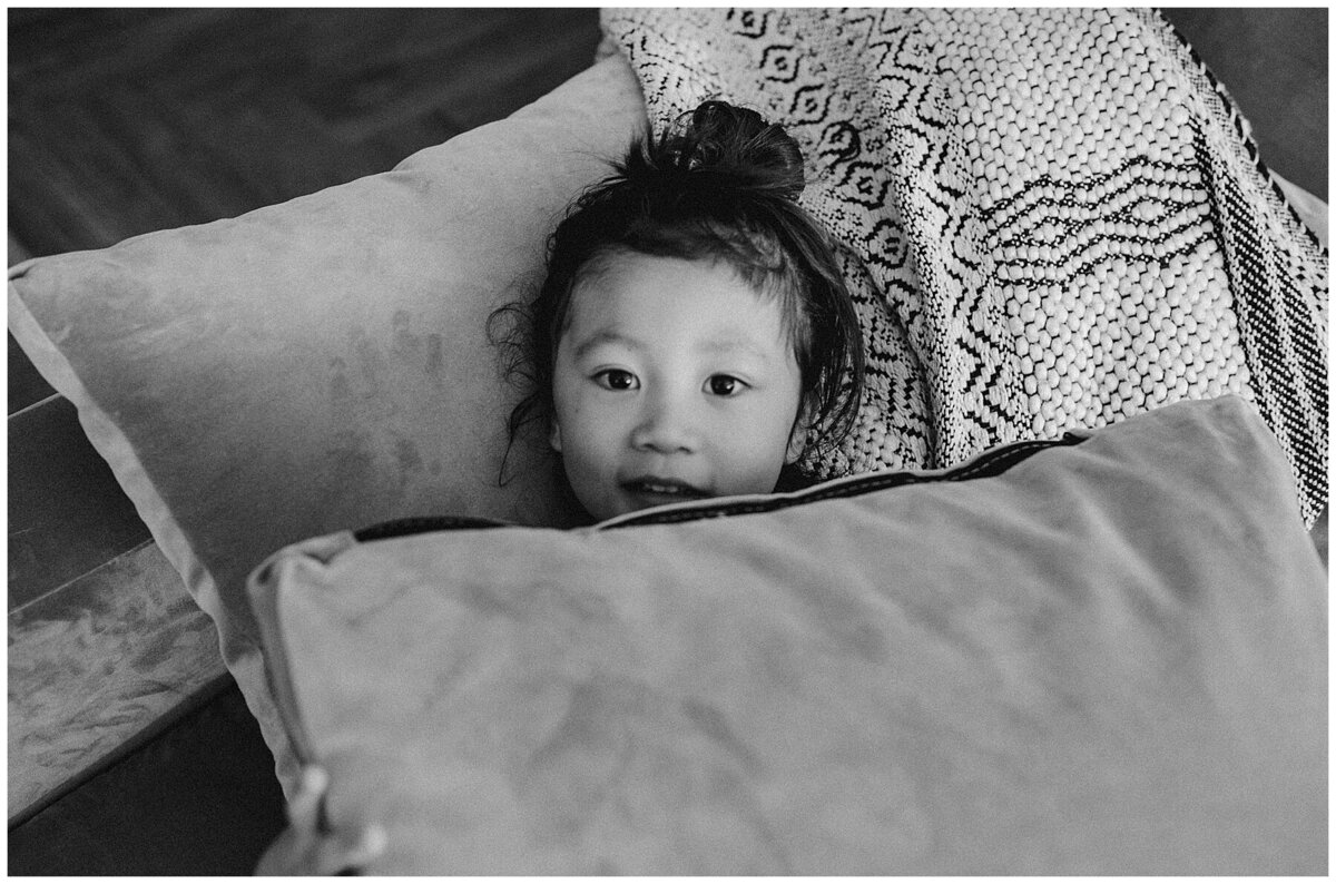 Child  with head peeping out of pillow at family photo session in Austin by Amber Vickey Photography