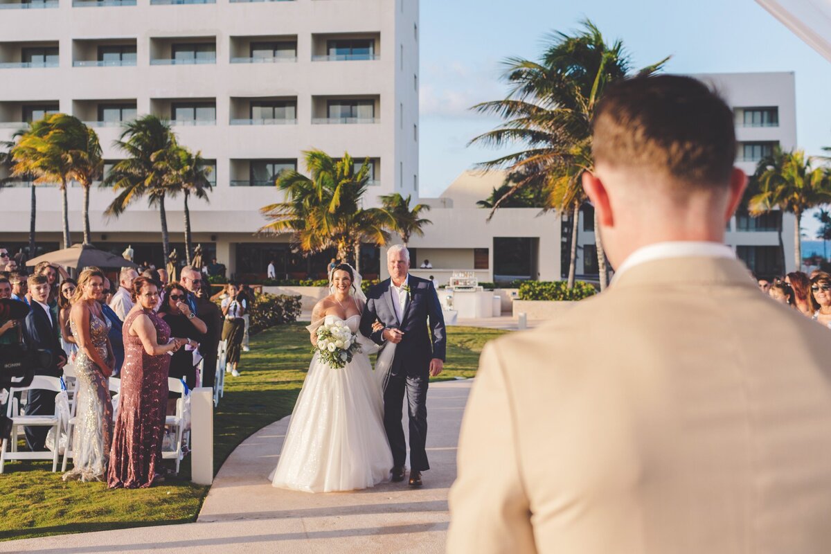 Bride walking down aisle to groom at wedding at Hyatt Ziva Cancun