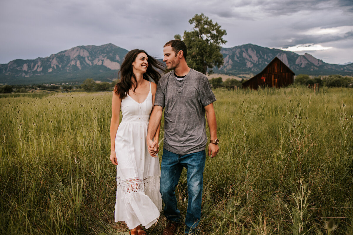 couple leans against a fence for engagement session in boulder colorado