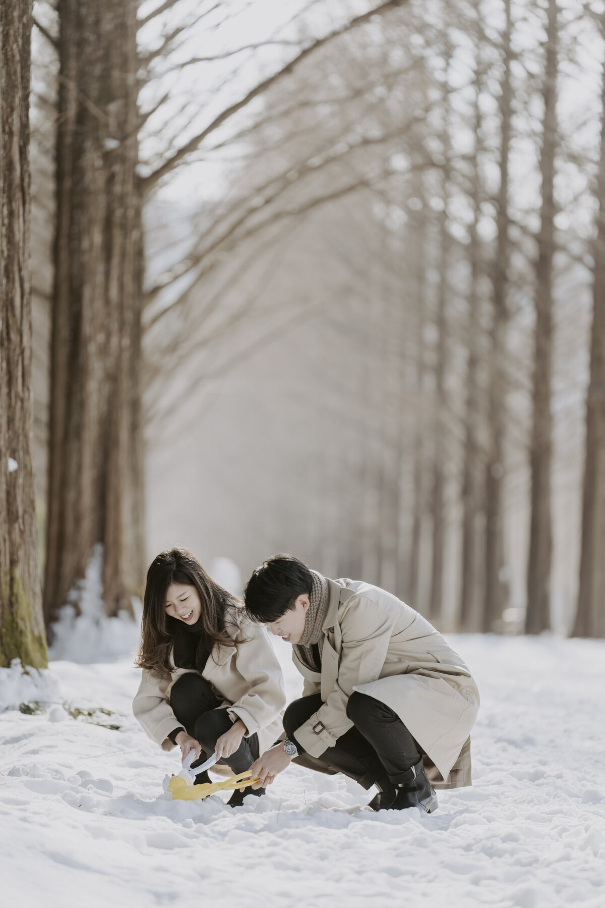 the couple playing in the snow and making their snow duck using their yellow duck maker tool