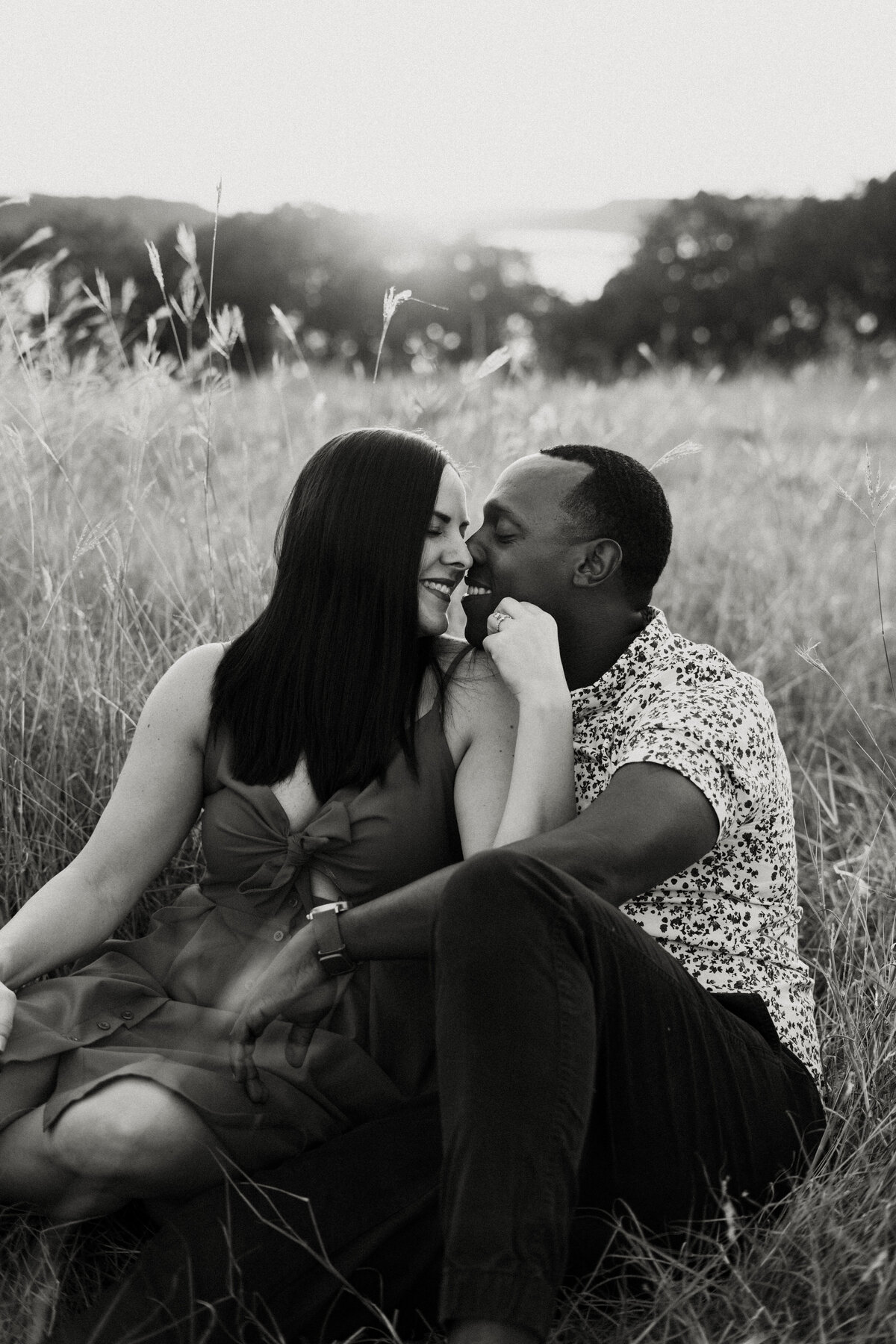 black and white image interracial couple sitting in field