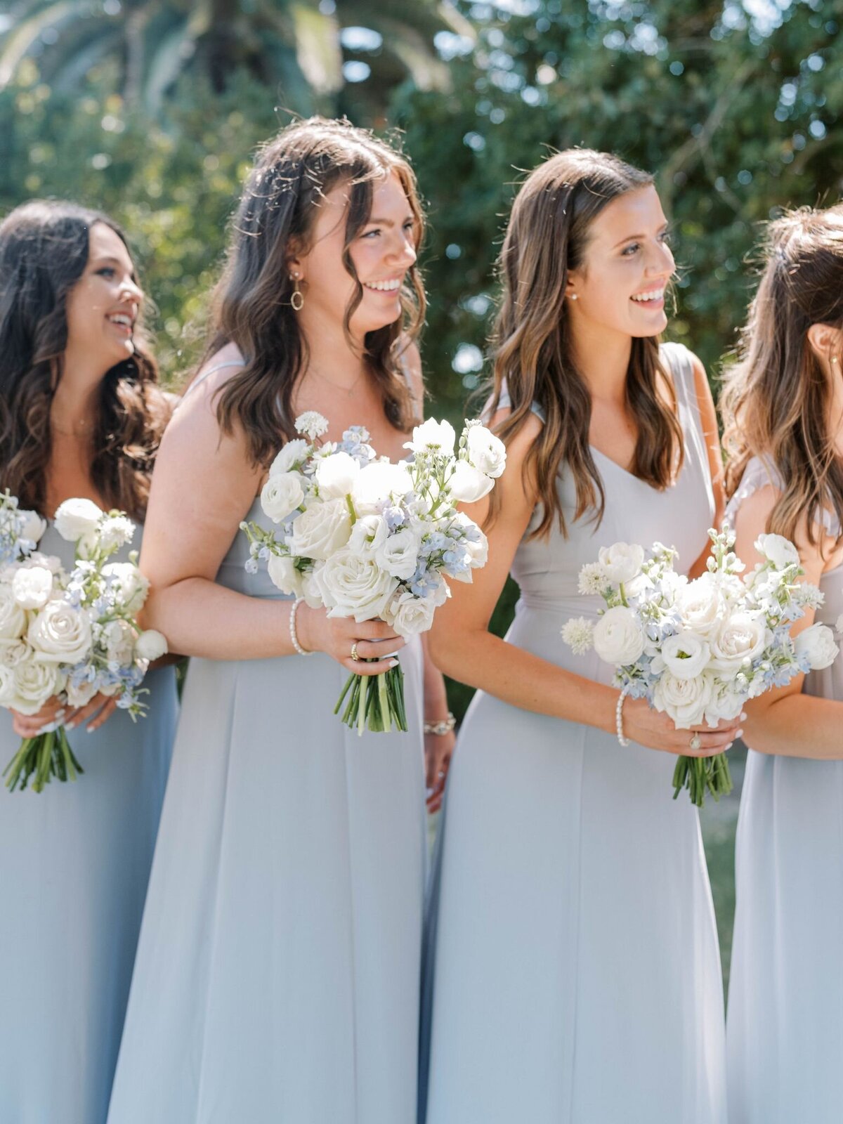 This line of bridesmaids all hold beautiful large white bouquets with baby blue accent flowers like their baby blue dresses.