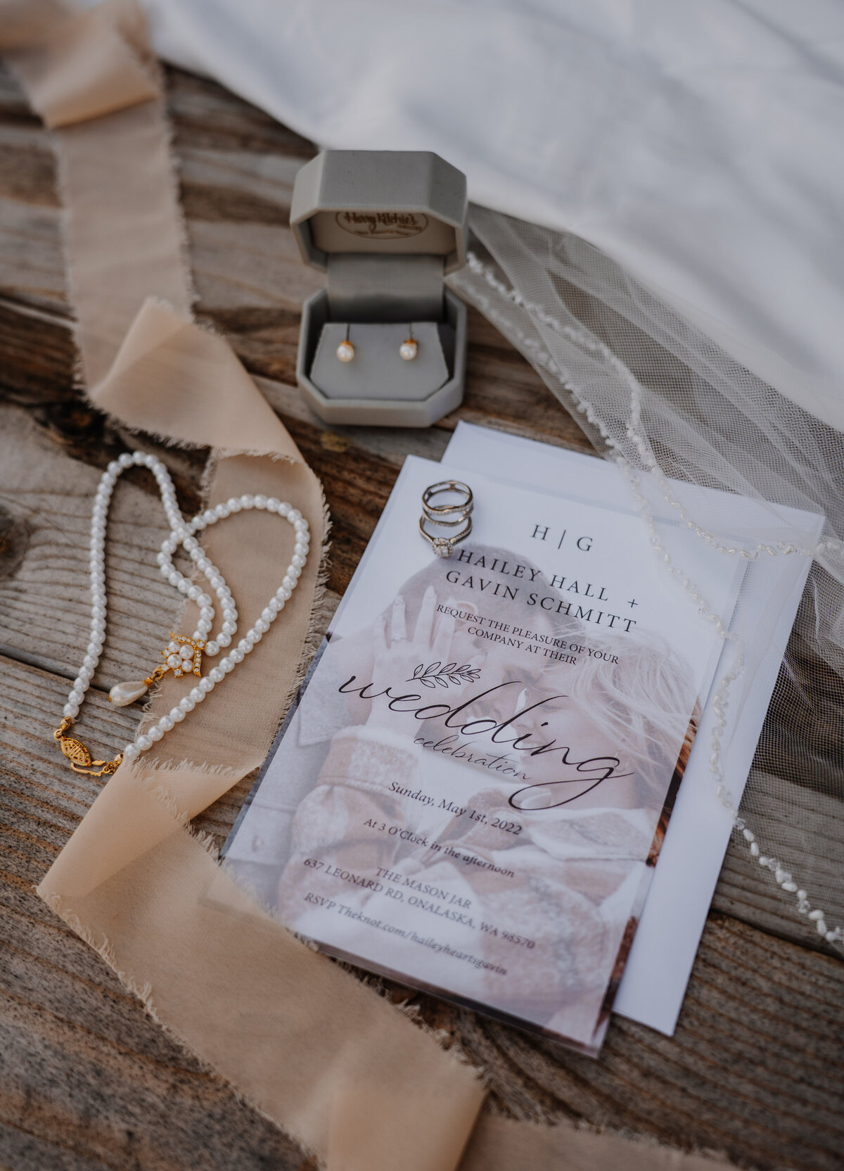 Wedding invitation next to pearl necklace and earings
