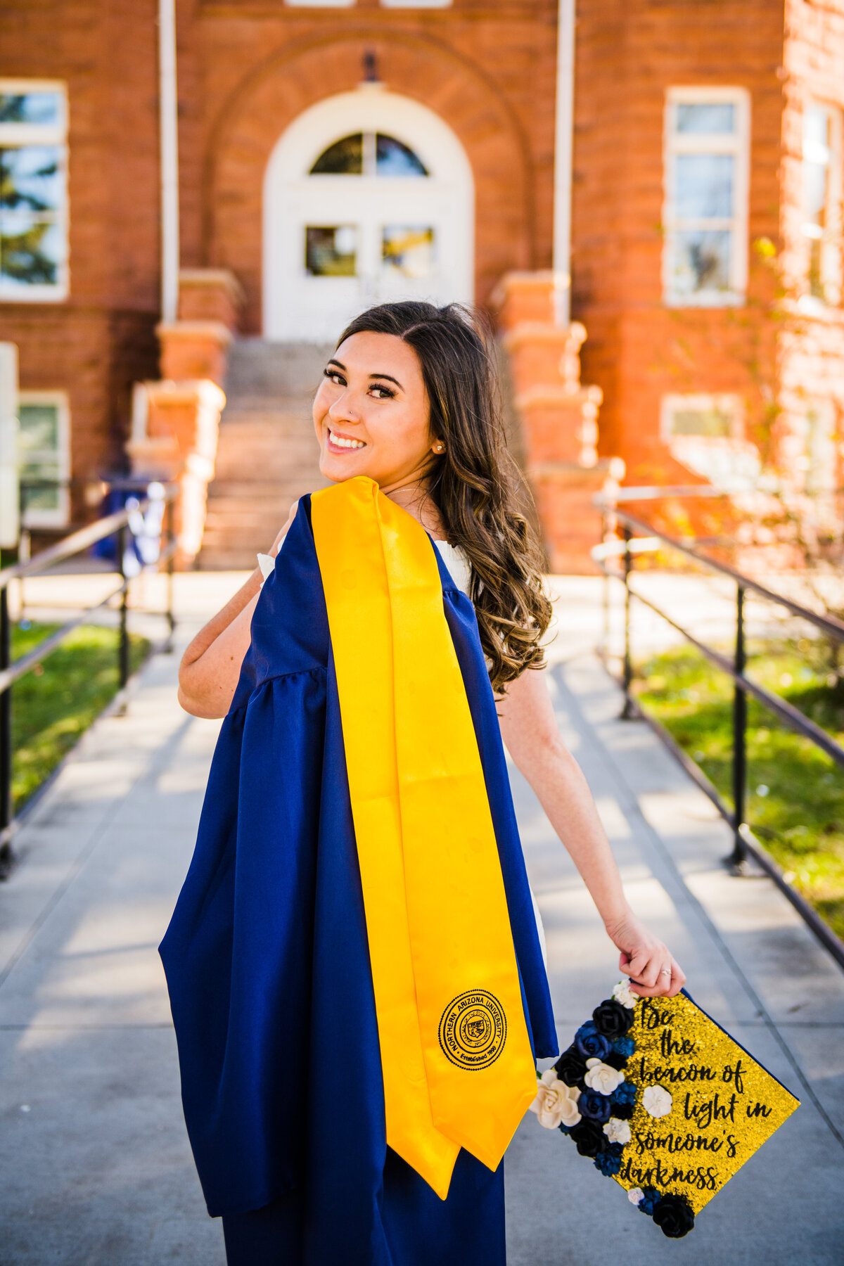 NAU senior holding cap and gown with stole Old Main Northern Arizona University Flagstaff