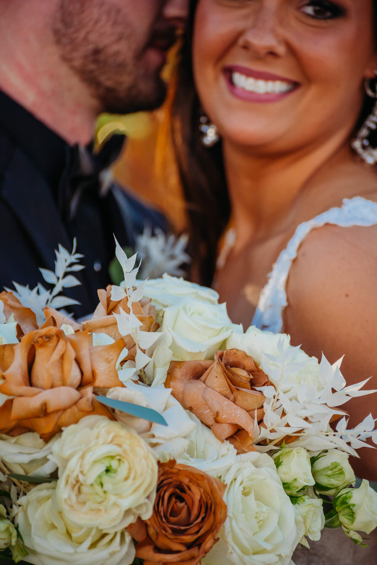 Photo of a brides bouquet while she smiles in the background