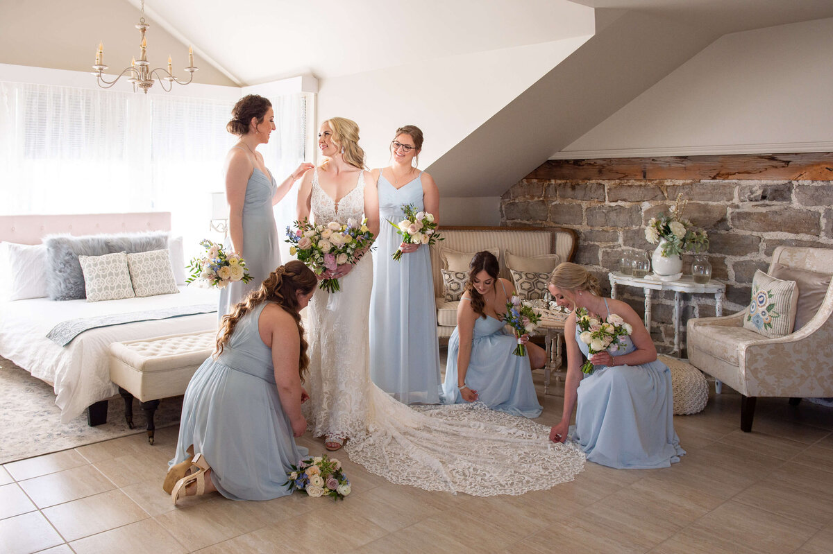 Bridesmaids in blue gowns help the bride get ready in the Farmhouse at Stonefields Estate.  Captured by Ottawa wedding photographer JEMMAN Photography