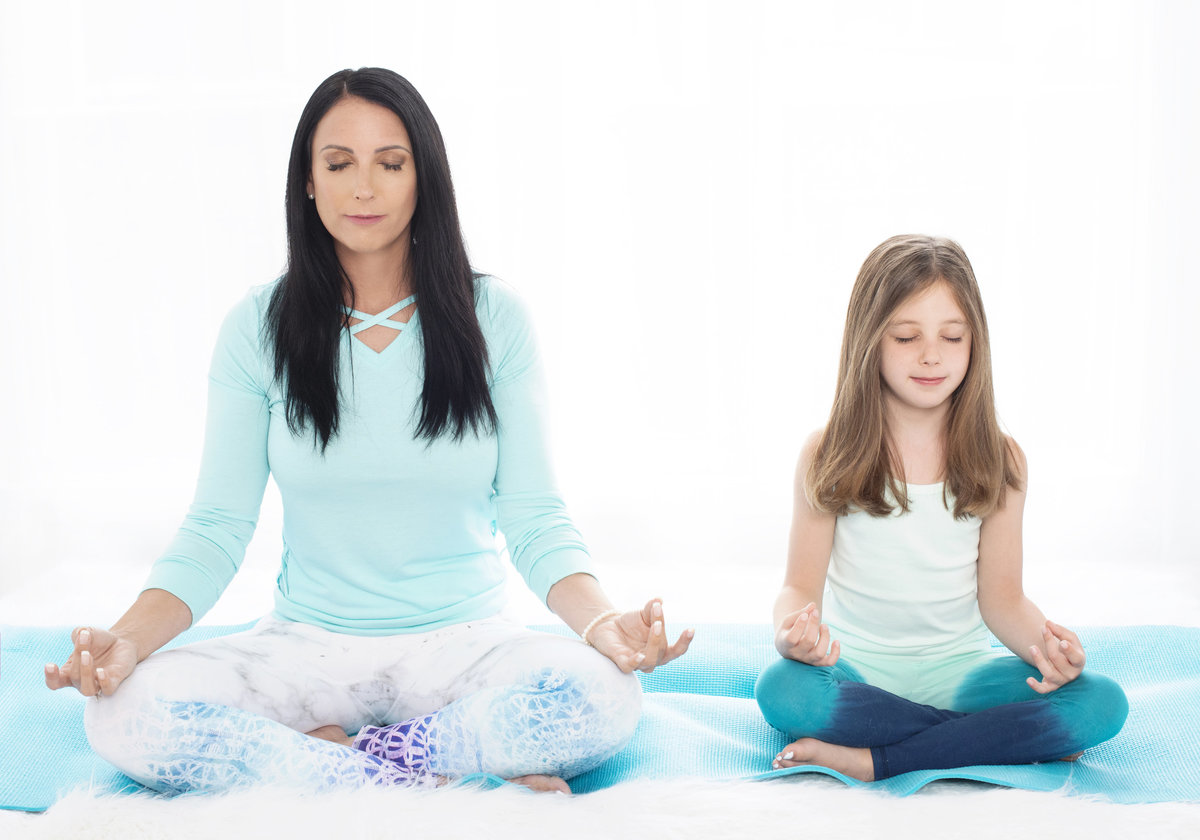yoga instructor busniess branding photo teaching young kids  breathing and  excercises sitting on floor with eyes closed
