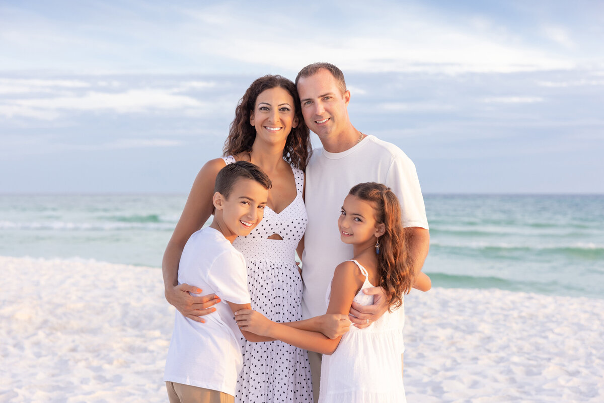 Two parents hugging their two kids as they all smile