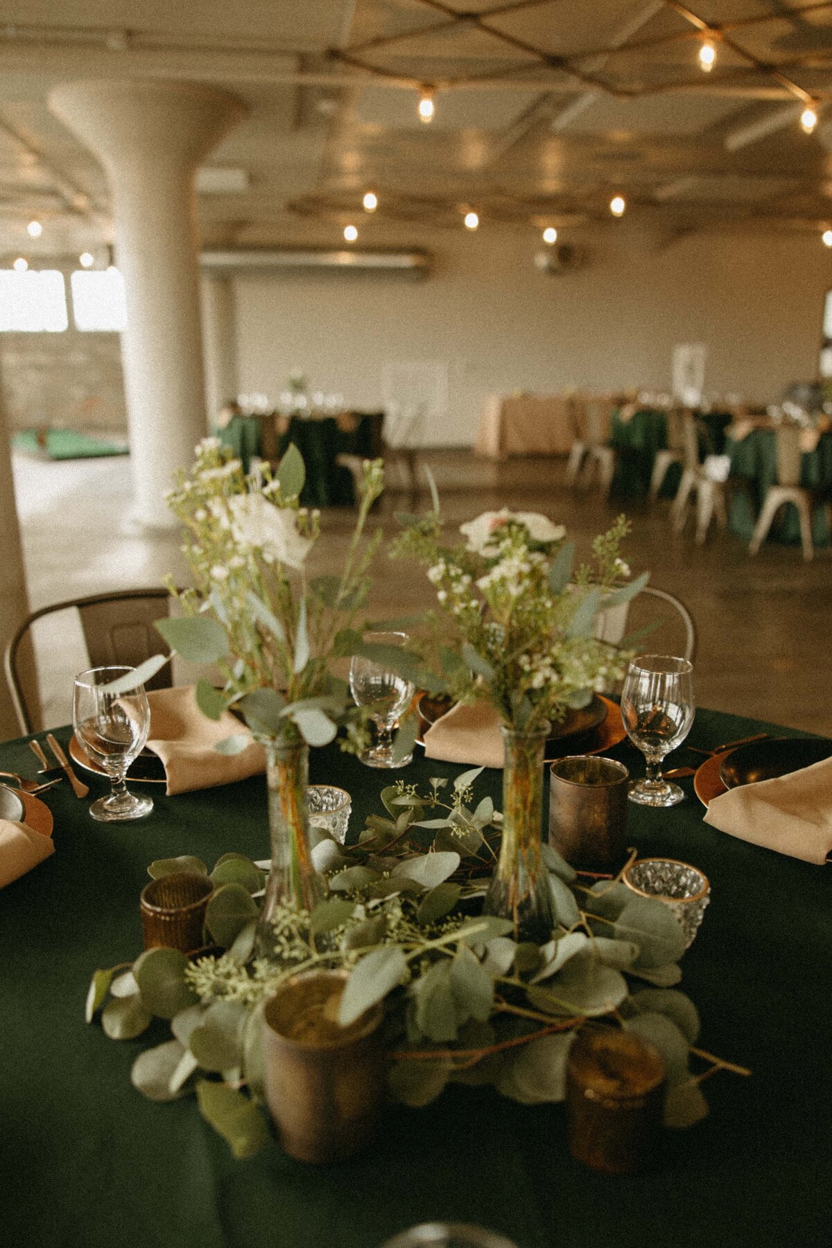 Elegant dining setup in a spacious room, ideal for Iowa weddings, featuring a table with green tablecloth, floral centerpieces, and crystal glassware.