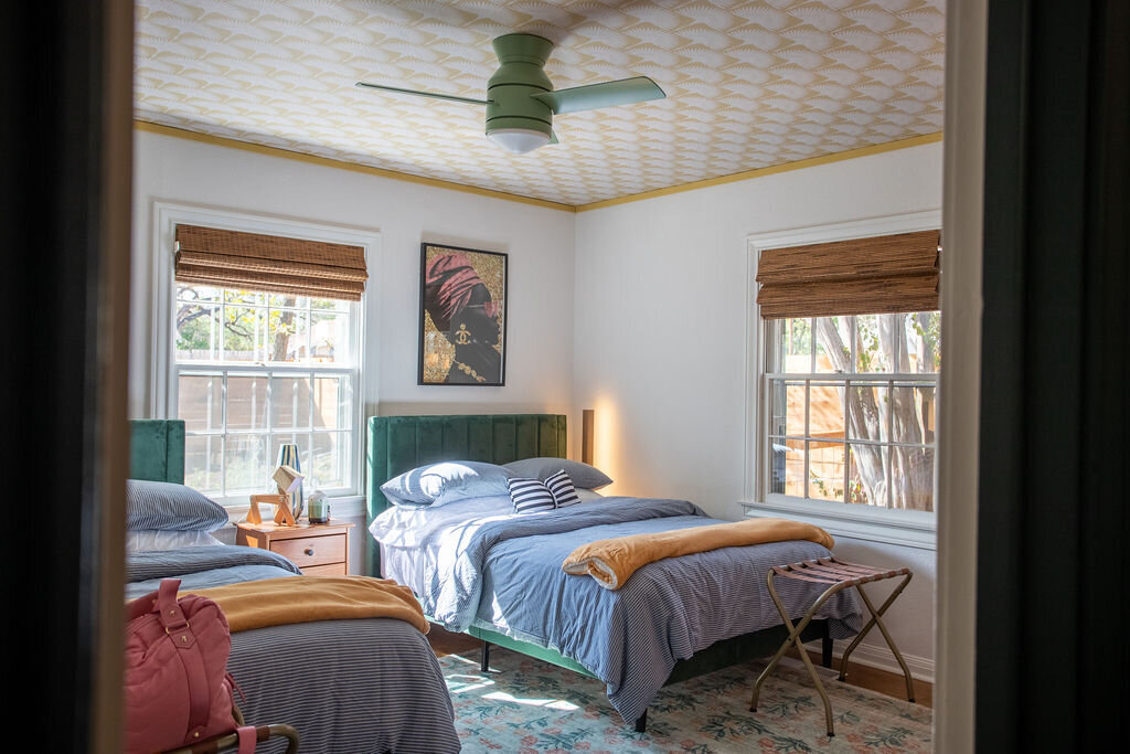 Two beds with plush bedding in this three-bedroom, two-bathroom mid-century house that sleeps 8 and boasts a unique experience in color, style, and lifestyle products located in the heart of Waco, TX.