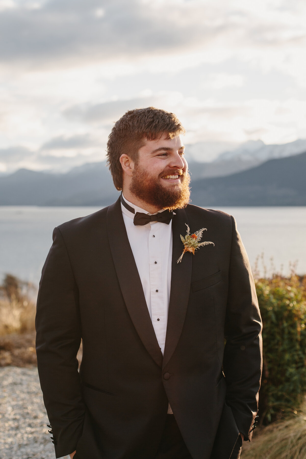 The Lovers Elopement Co - groom smiles at side of lake in Queenstown