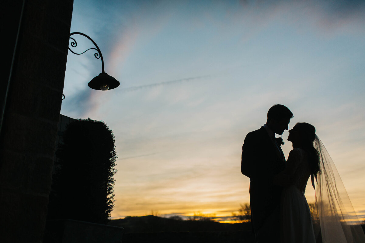 Silhouette of a bride and groom stood outside Tithe Barn