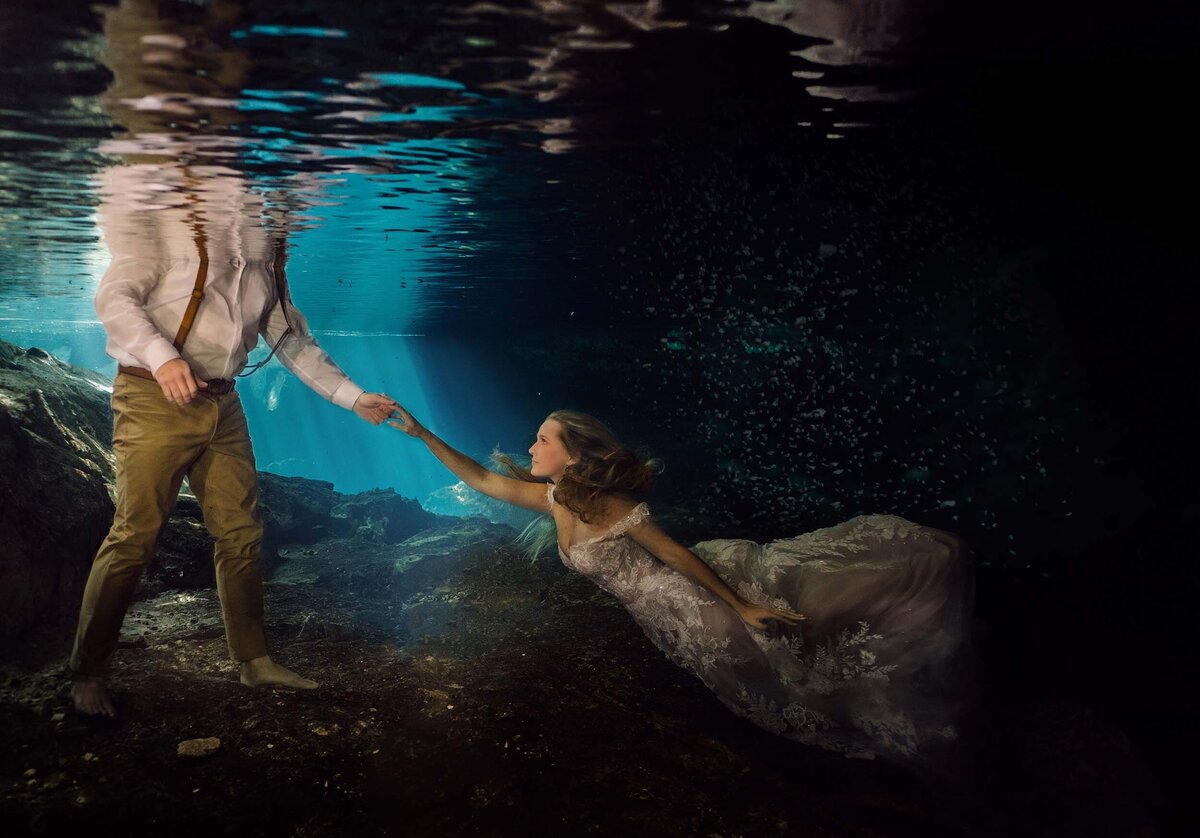 Groom reaching for bride underwater during trash the dress (TTD( in Riviera Maya