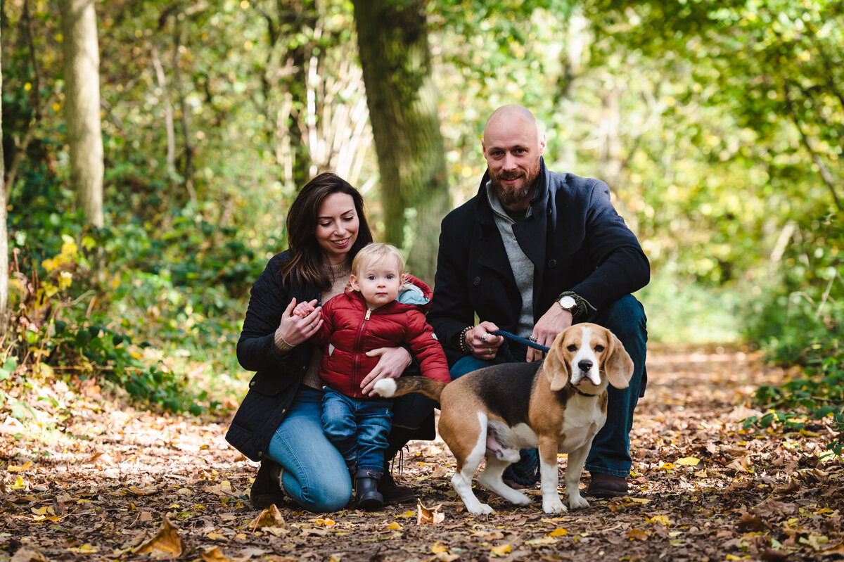 Family with their dog kneeling down at rutland water autumn photoshoot with amanda forman photography