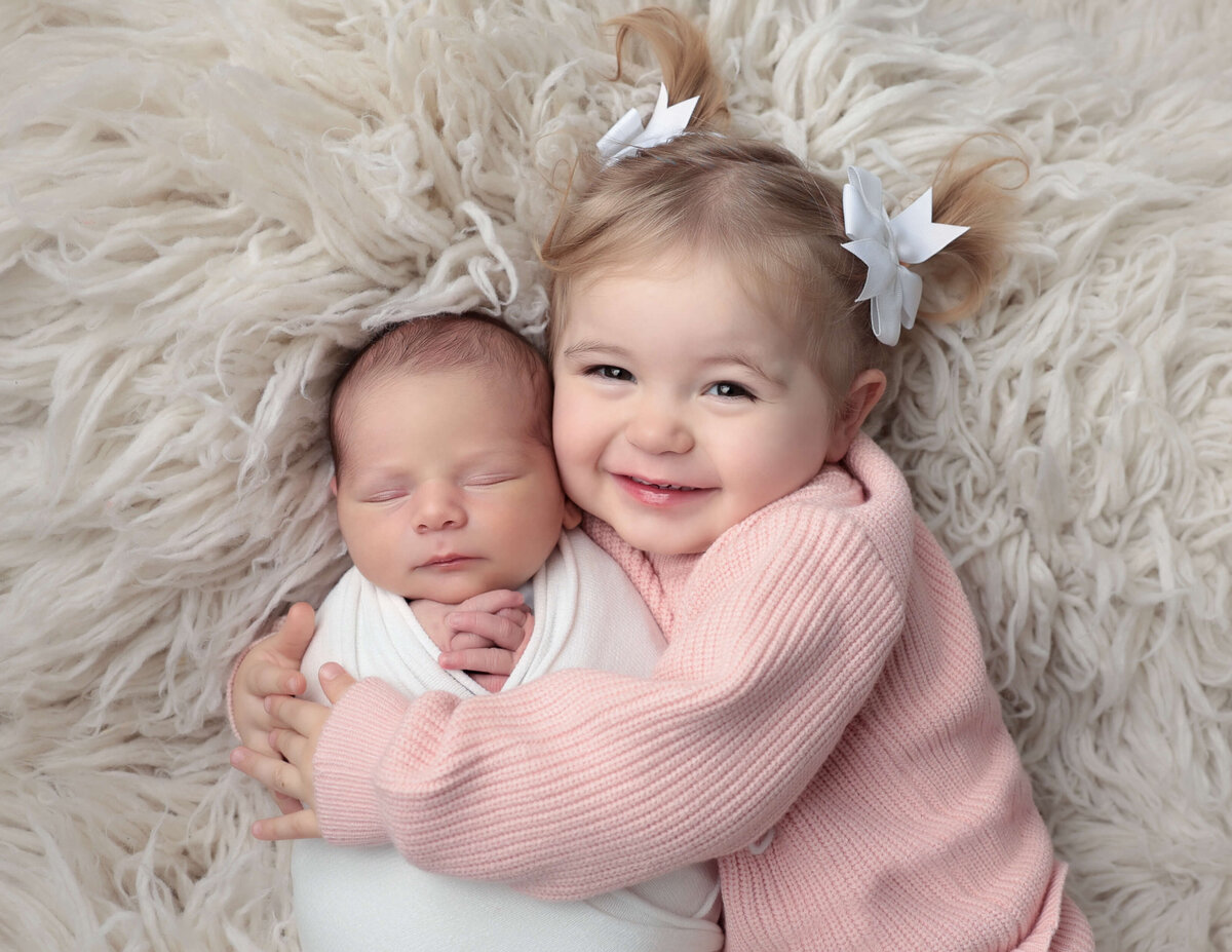 Newborn boy posed with big sister at our Rochester, Ny studio.