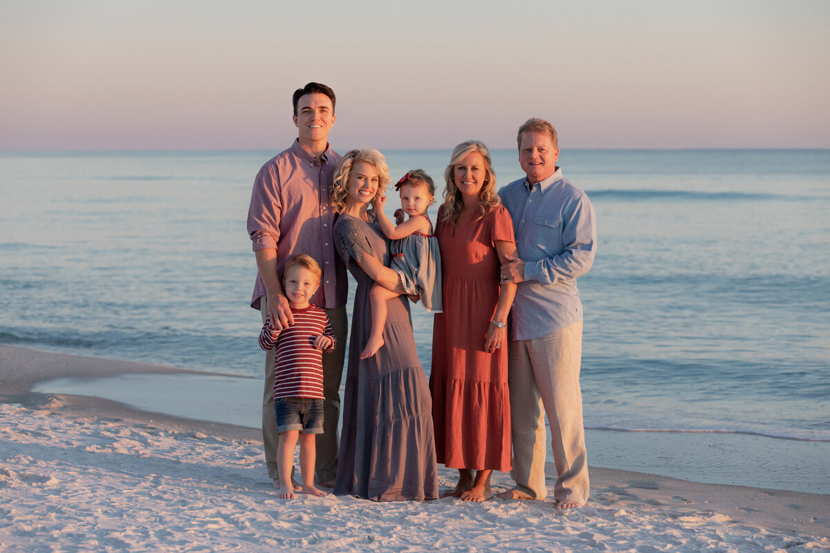 A family with small children smiling together at the beach