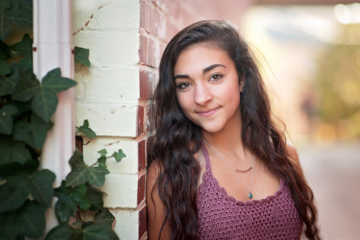 Senior session of young woman standing against a brick wall