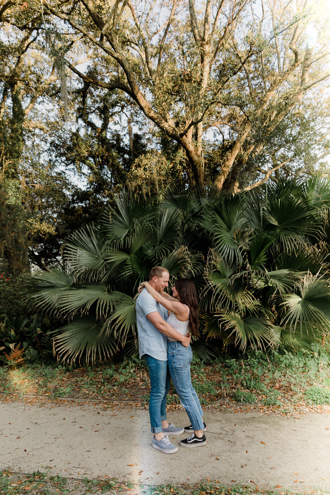 couple hugging in front of palm tree for engagement session