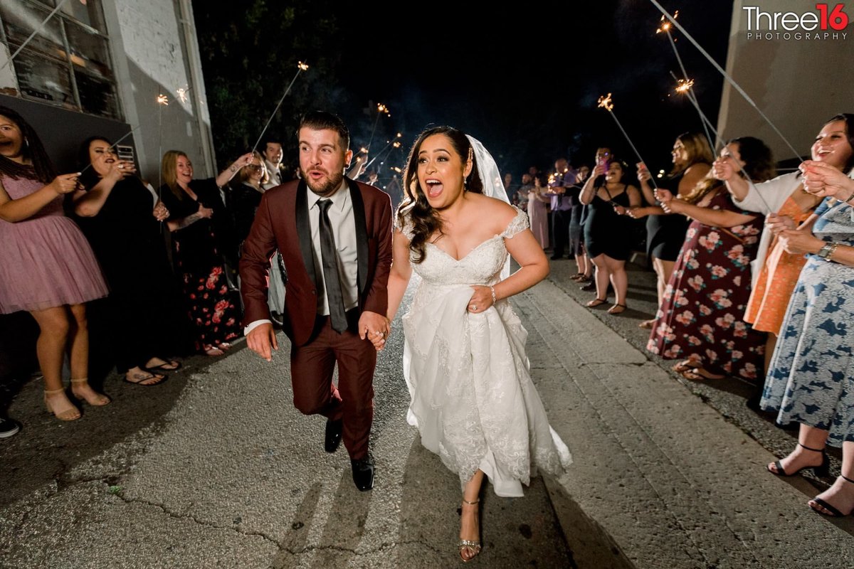 Bride and Groom exit the reception running under a human tunnel of sparklers