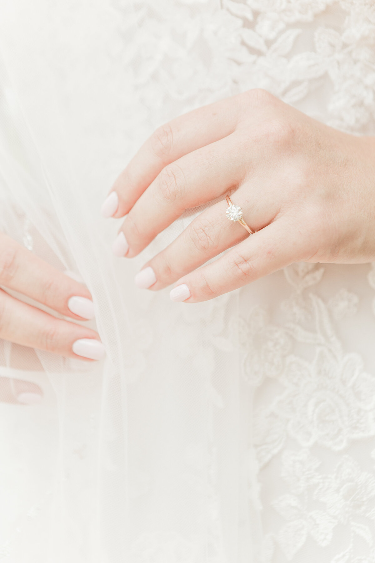 A close up image of the bride's hands. She is holding her veil gently. The image features her engagement ring.
