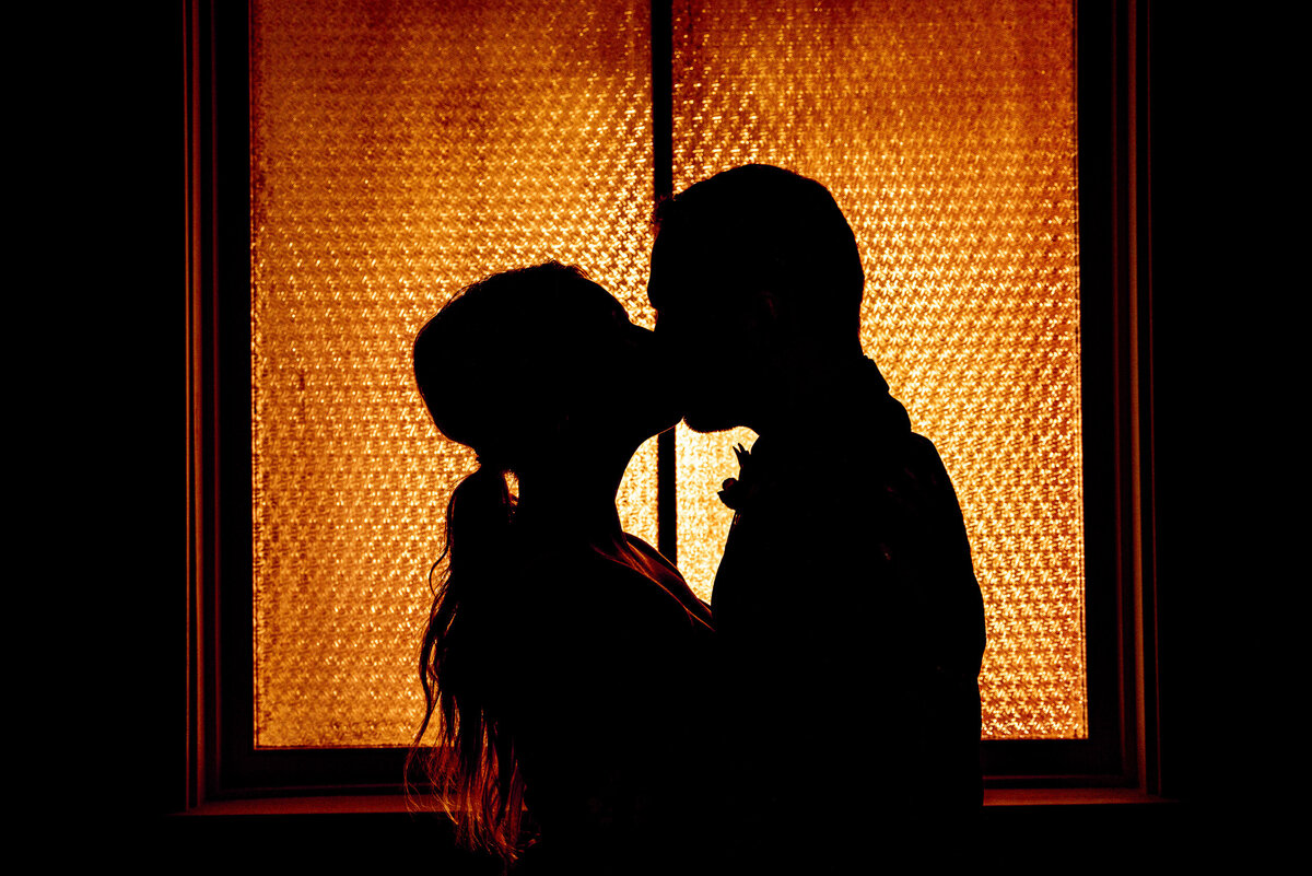 Bride and groom kiss in silhouette