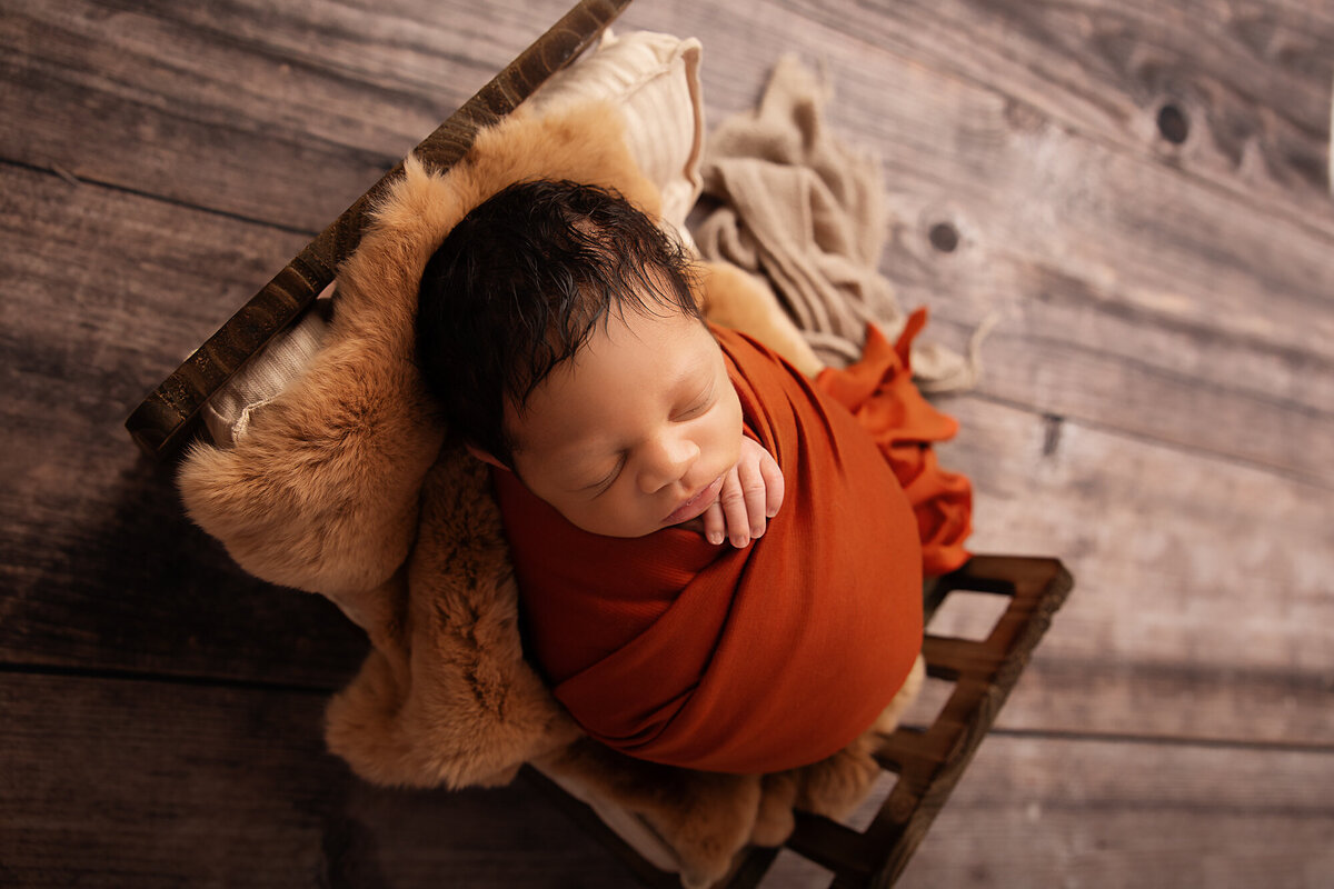 newborn boy in wood bed