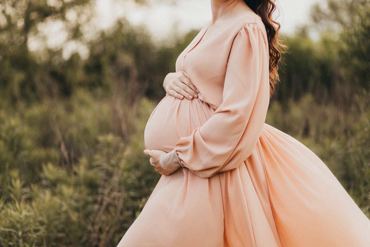 woman holds her pregnant belly for maternity pictures in houston.