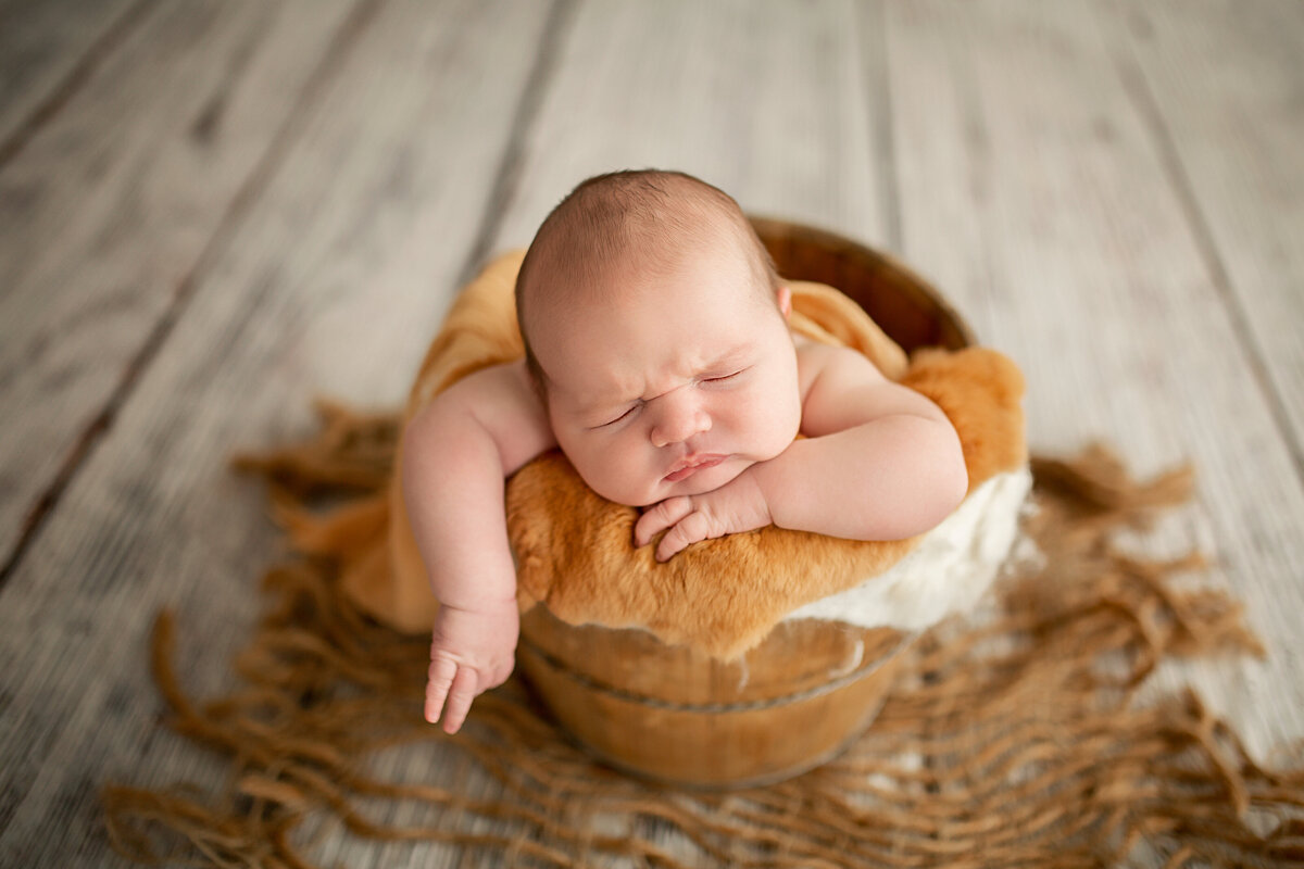 newborn baby boy in gold bucket pose