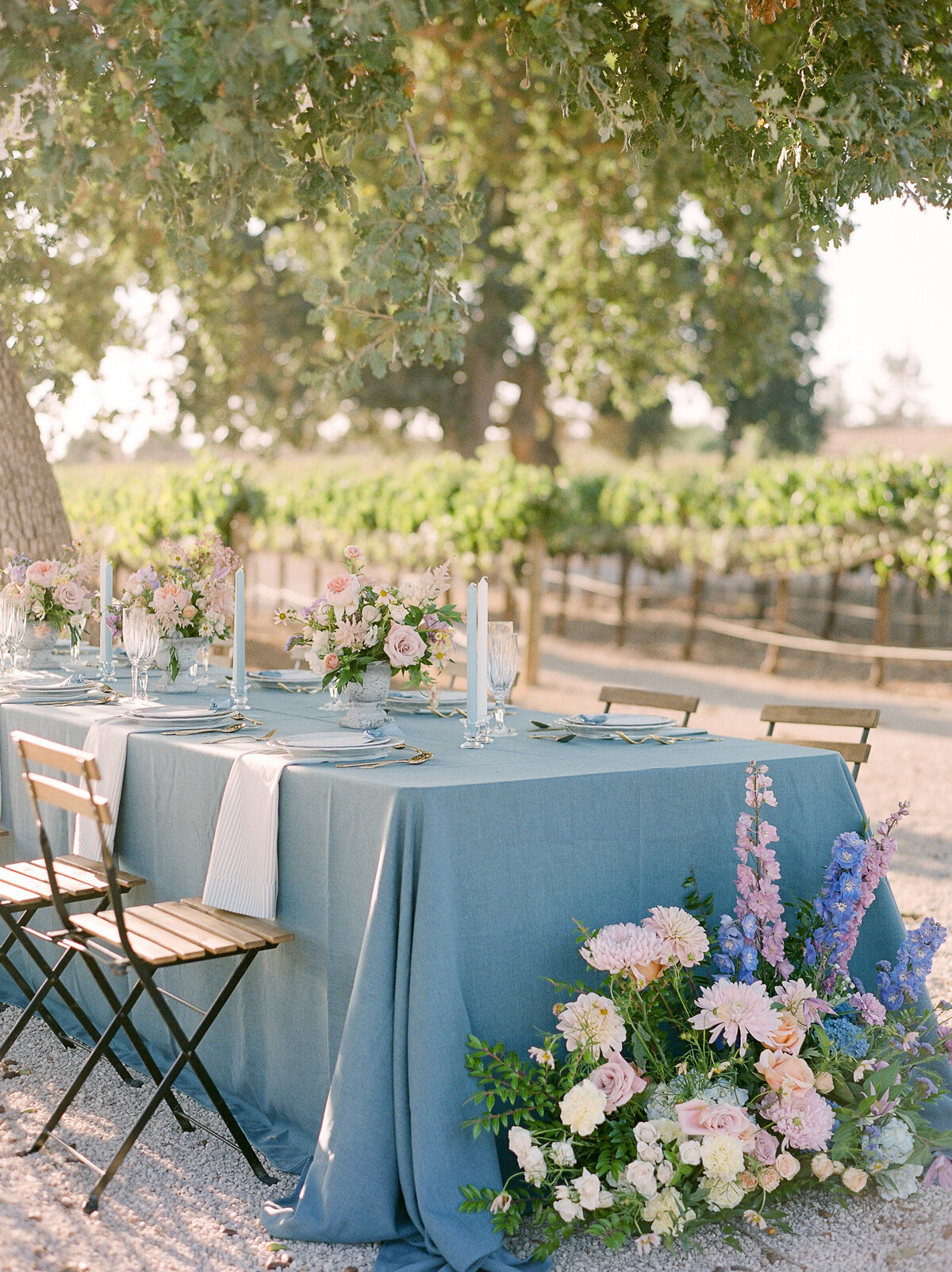 a table with florals and candles out in a vineyard  in california