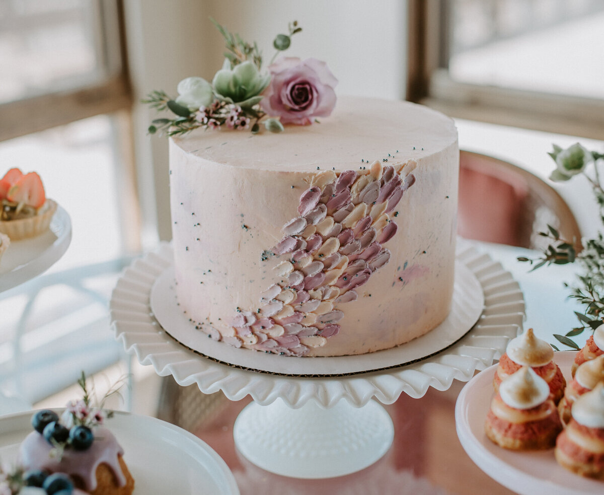 Pink elegant wedding cake with trendy spatula painting icing technique, topped with purple flowers, by Lemonberry Pastries, contemporary cakes & desserts in Calgary, Alberta, featured on the Brontë Bride Vendor Guide.