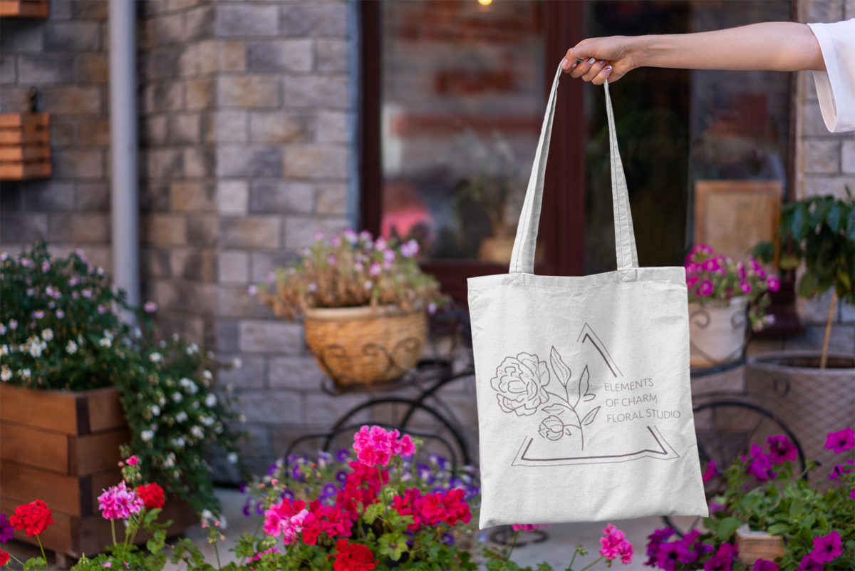 mockup-featuring-a-woman-s-hand-holding-a-tote-bag-by-some-flower-pots-3137-el1