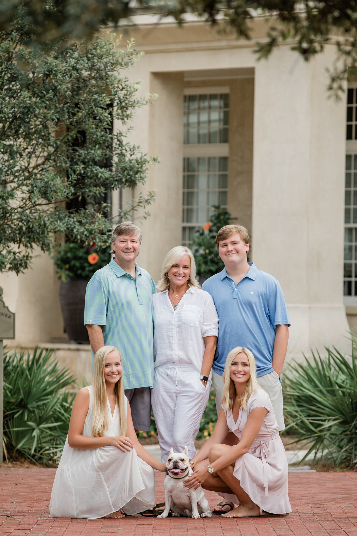 Parents smiling with their older children and a small dog