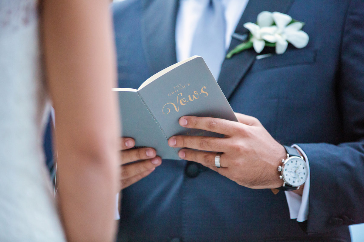 Groom holding a vow book while reading his vows
