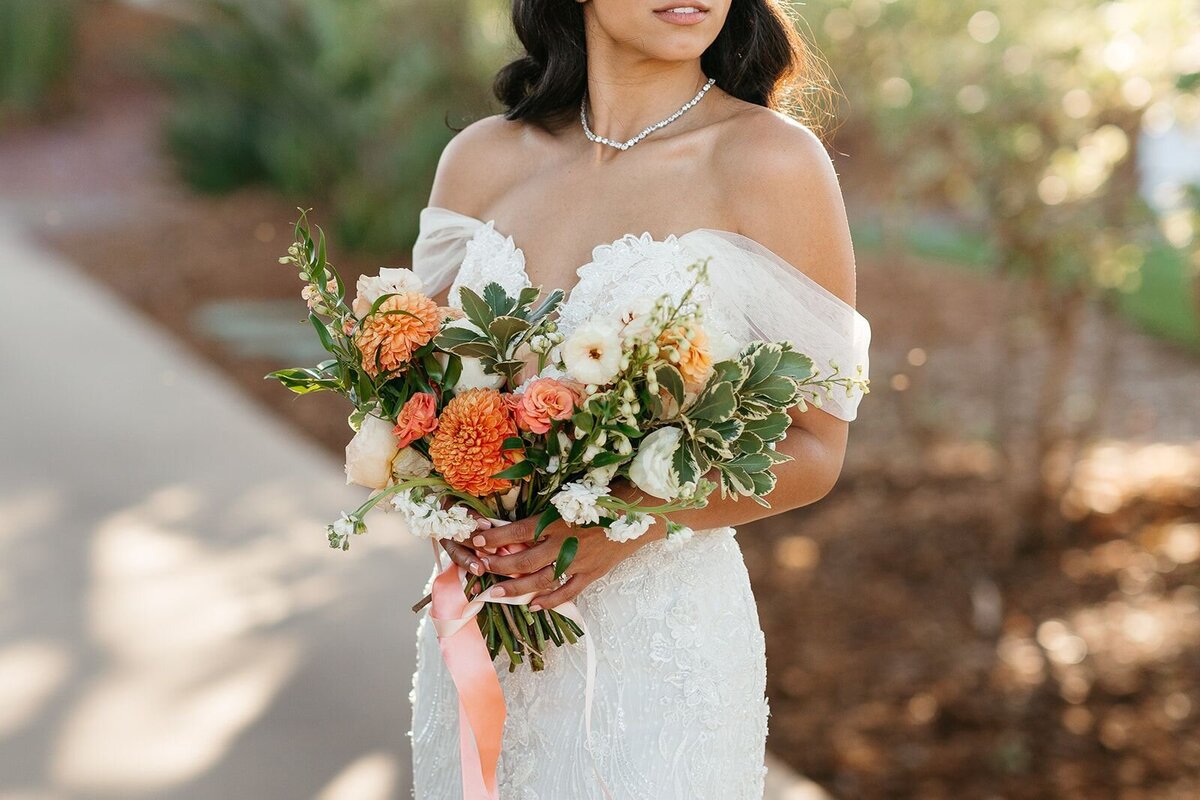 A closeup of the bride's bouquet of orange, yellow and dust rose flowers.