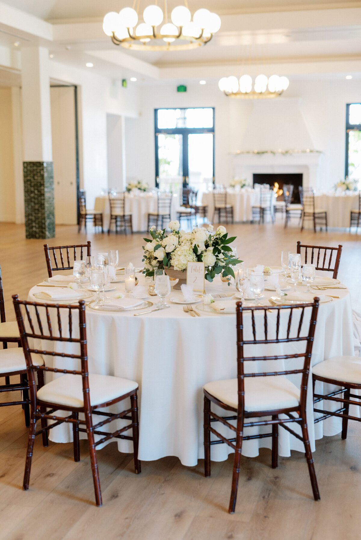 A wedding dining table holding white bouquets.