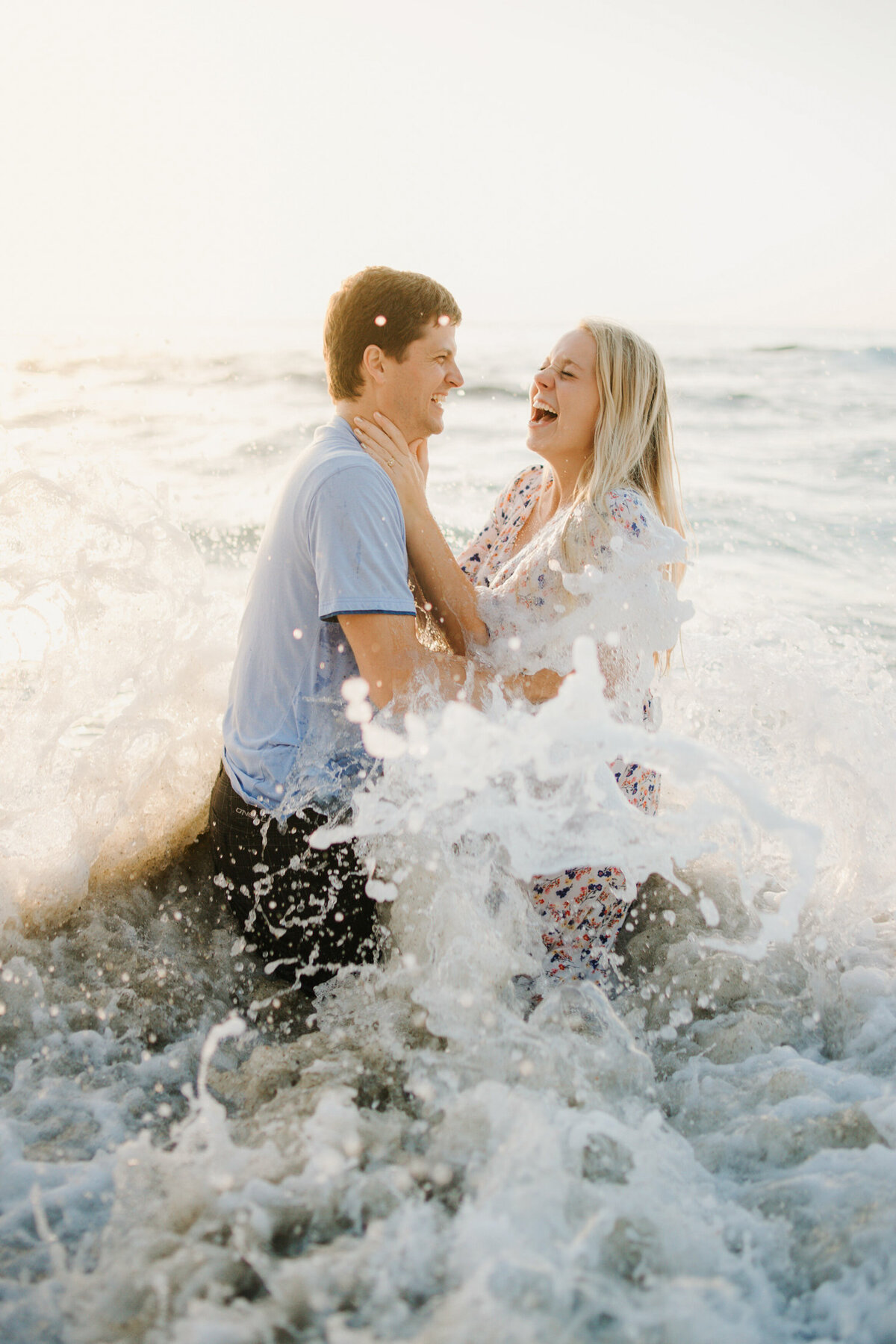 stunning photo of couple being splashed by the waves in san diego during couples photo session