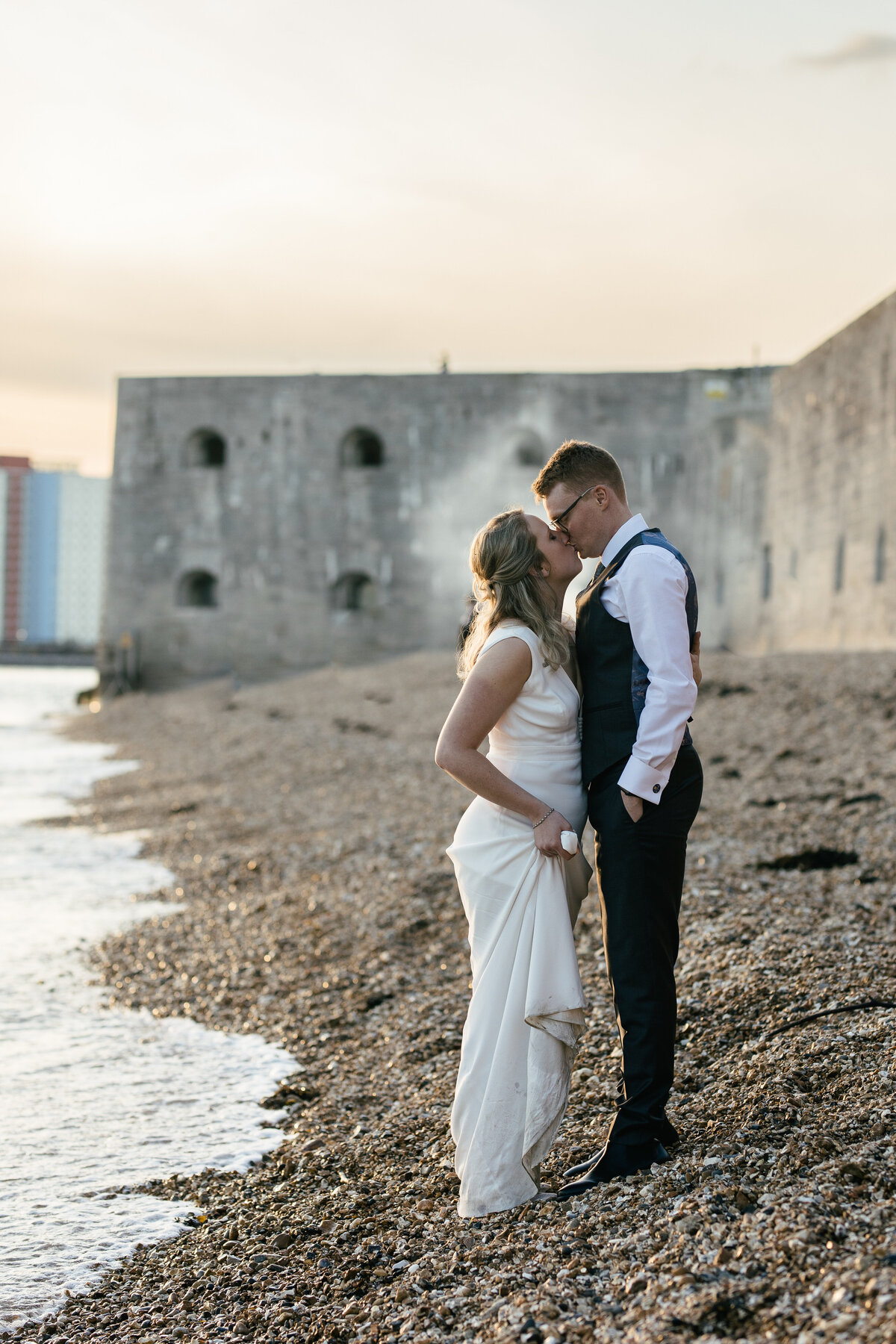 bride and groom stop on beach during sunset for thier couple photoshoot by thier wedding photographer